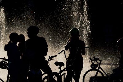 Silhouette men with bicycle standing at night