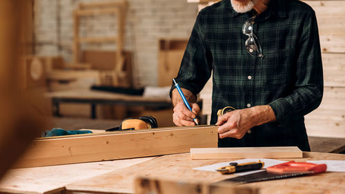 Midsection of carpenter working in workshop