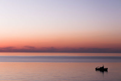 Silhouette boat in sea against sky during sunset