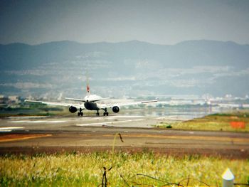 Airplane flying over runway against sky