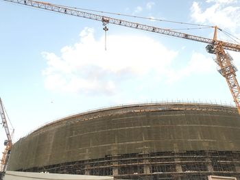 Low angle view of crane at construction site against sky