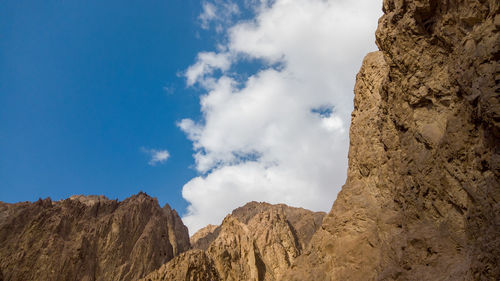 Low angle view of rocky mountains against blue sky