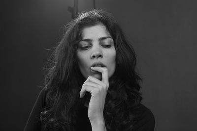 Portrait of beautiful young woman against black background