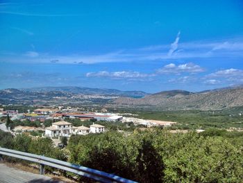 Scenic view of townscape and mountains against blue sky