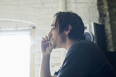 Profile of a young man smoking.