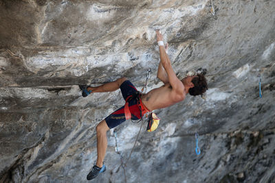 Midsection of man with arms raised on rock