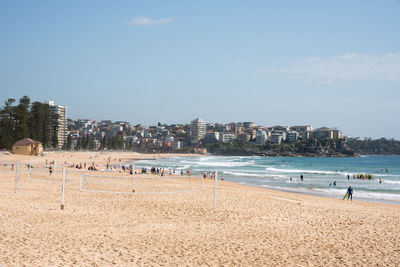 People on beach against sky in city