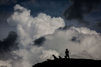 Low angle view of silhouette man standing on mountain against sky