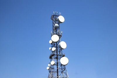 Low angle view of communications tower against clear blue sky