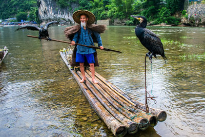 Men with birds on wooden rafts in lake