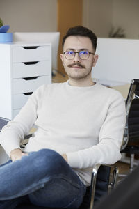 Portrait of confident businessman sitting on chair at office