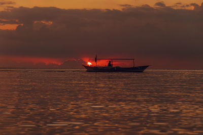 Silhouette boat in sea against sky during sunset