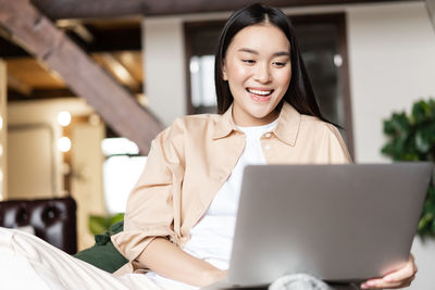 Portrait of smiling young woman using laptop at home