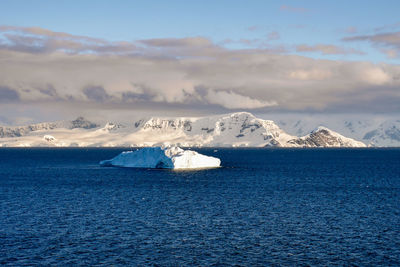 Scenic view of sea and snowcapped mountains against sky