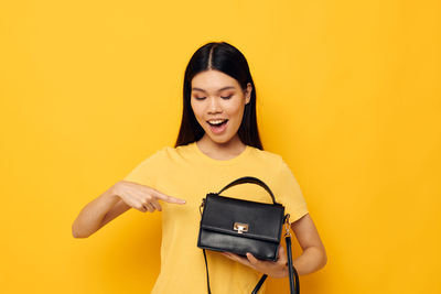 Young woman with purse against yellow background