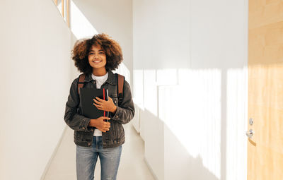 Female student with book walking in corridor