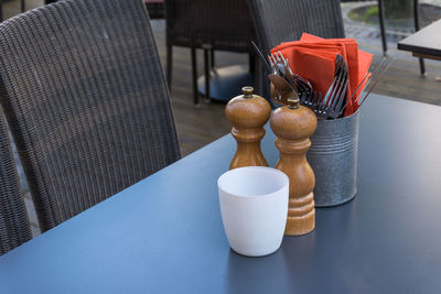 High angle view of pepper mills with cutlery and container on table in restaurant