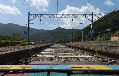 Railroad tracks by mountain against sky