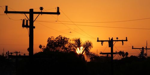 Low angle view of silhouette electricity pylon against sky during sunset