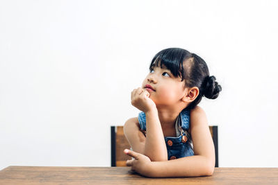 Girl looking away while sitting on table