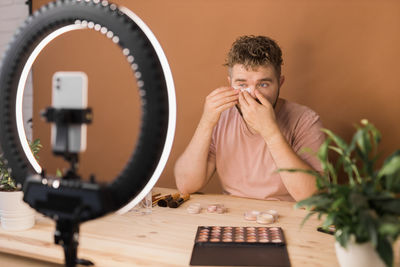 Young man using mobile phone while sitting on table