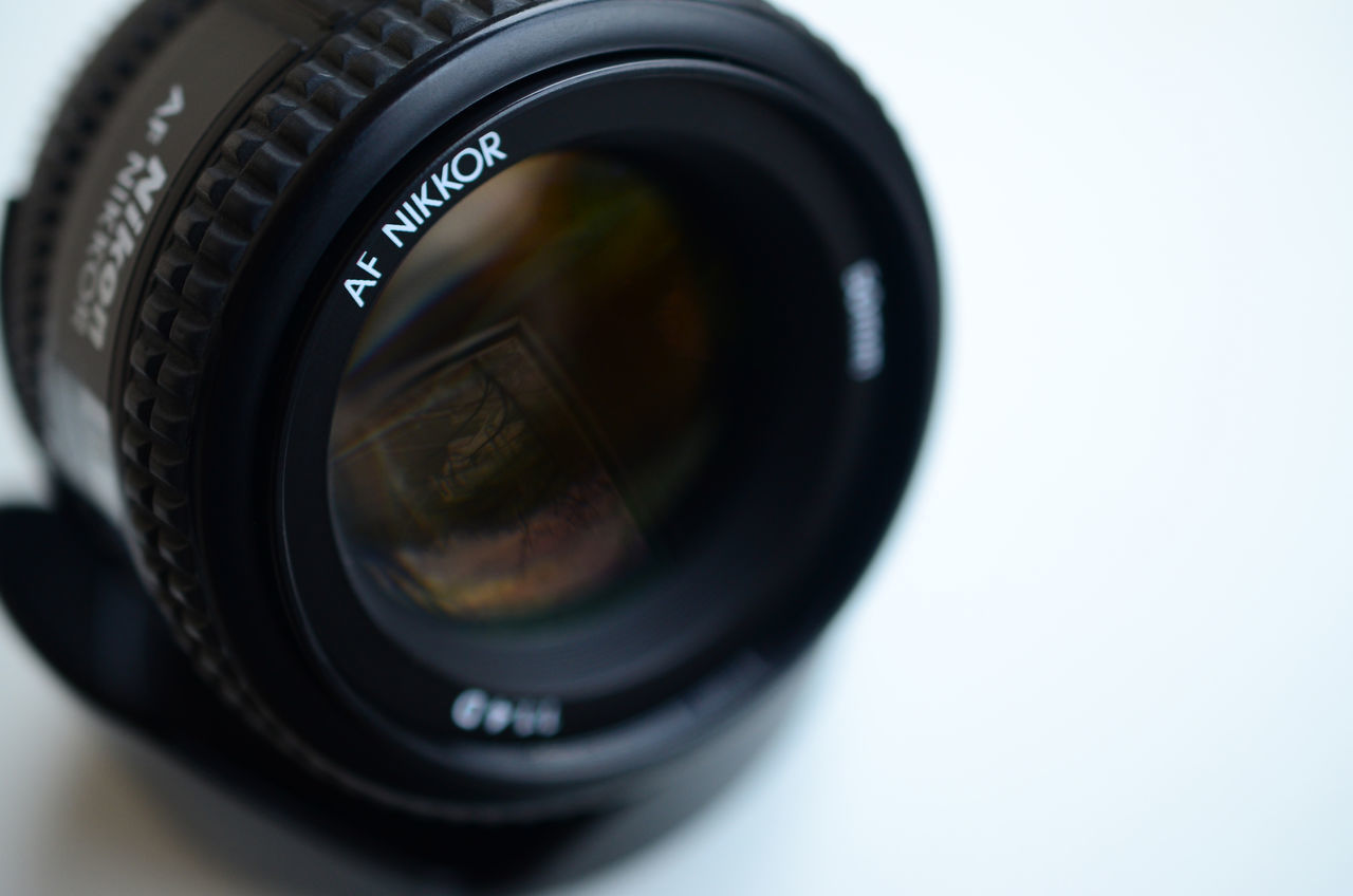 CLOSE-UP OF CAMERA LENS ON WHITE BACKGROUND