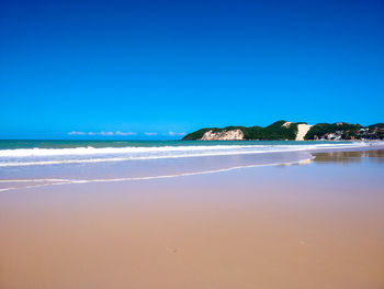 Scenic view of beach against clear blue sky