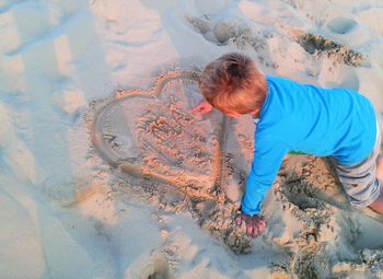 High angle view of boy writing on sand at beach