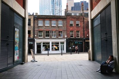 People on footpath by buildings in city