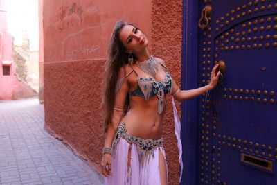 Portrait of beautiful young bellydancer wearing her belly dancing outfit and standing to a blue door
