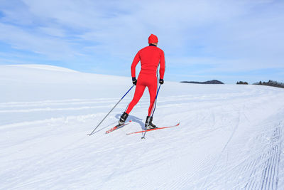 Rear view of man skiing on snowcapped mountain against sky