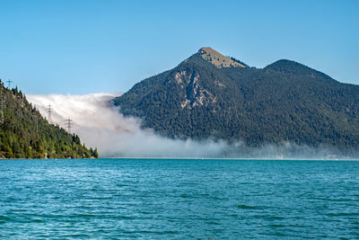 Scenic view of sea and mountains against clear blue sky