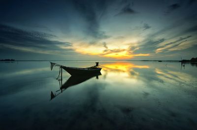 Boat moored in sea against sky during sunset