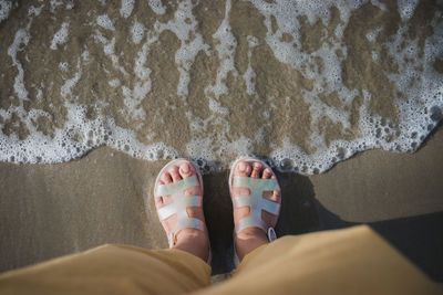 Low section of man standing on beach