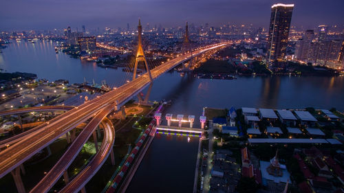 High angle view of illuminated city by buildings at night