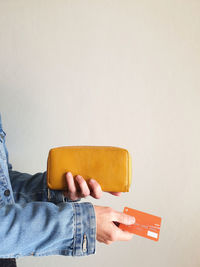 Close-up of hand holding sofa against orange wall