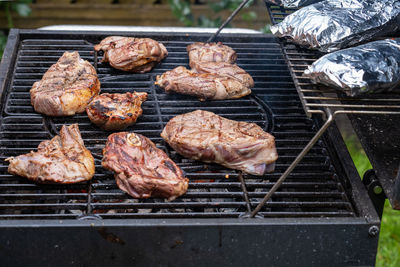 Pieces of fresh meat and fish in foil are laid out on a grill grate. barbecue cooking. 