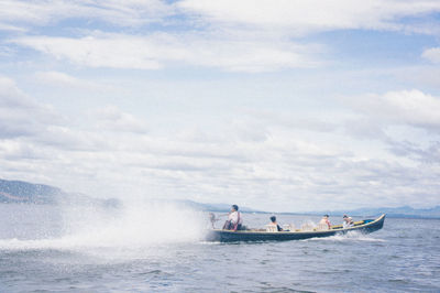 People sailing on motorboat in sea against sky