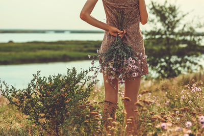 Young woman is standing back and holding a bouquet of flowers in nature. steppe autumn flowers.