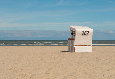 Hooded chair on beach against sky