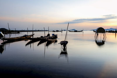 Boats moored in sea against sky during sunset