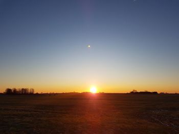 Scenic view of field against clear sky during sunset