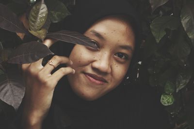 Close-up portrait of smiling young woman with leaves