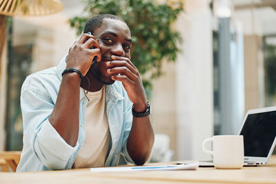 Young woman using mobile phone while sitting in office