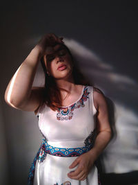 Beautiful young woman standing against wall