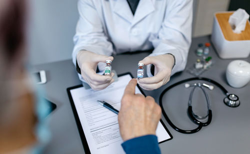 Midsection of doctor giving medicines to patient