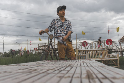 Man standing by railing against sky