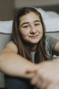Portrait of smiling pre-adolescent girl sitting at home