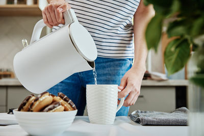 Woman pouring water from kettle for brewing tea