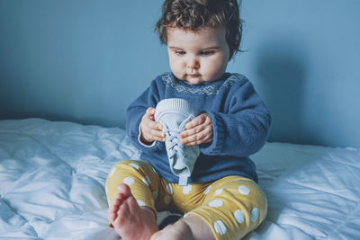 Baby girl playing with shoe on bed